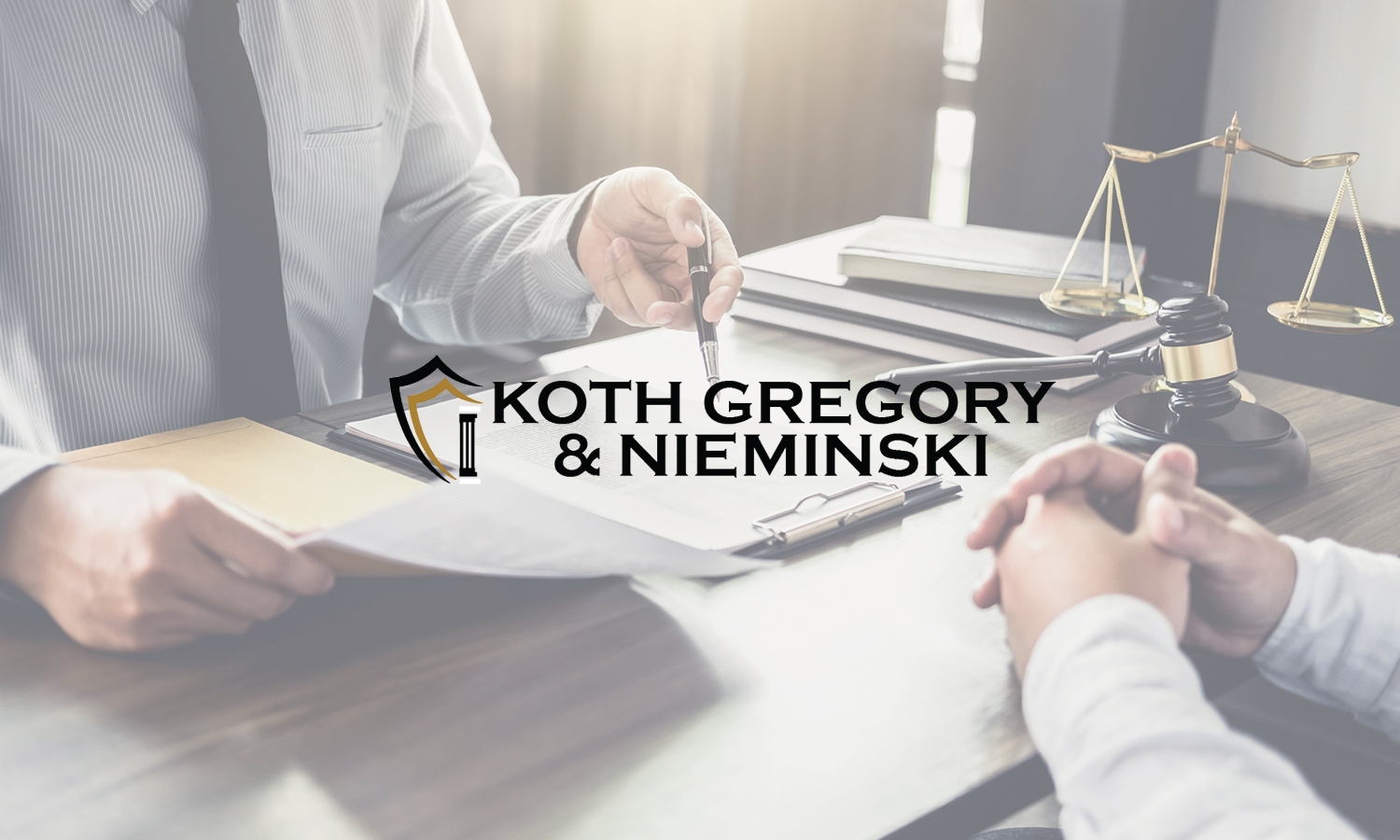 Two people in formal attire sit at a desk with legal documents, a gavel, and scales of justice; the logo Koth Gregory & Nieminski is prominently displayed in the center.